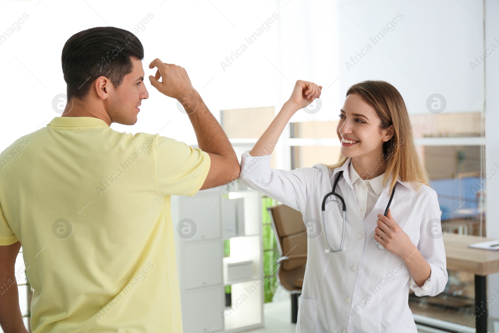 Photo of Doctor and patient doing elbow bump instead of handshake in clinic. New greeting during COVID-19 pandemic