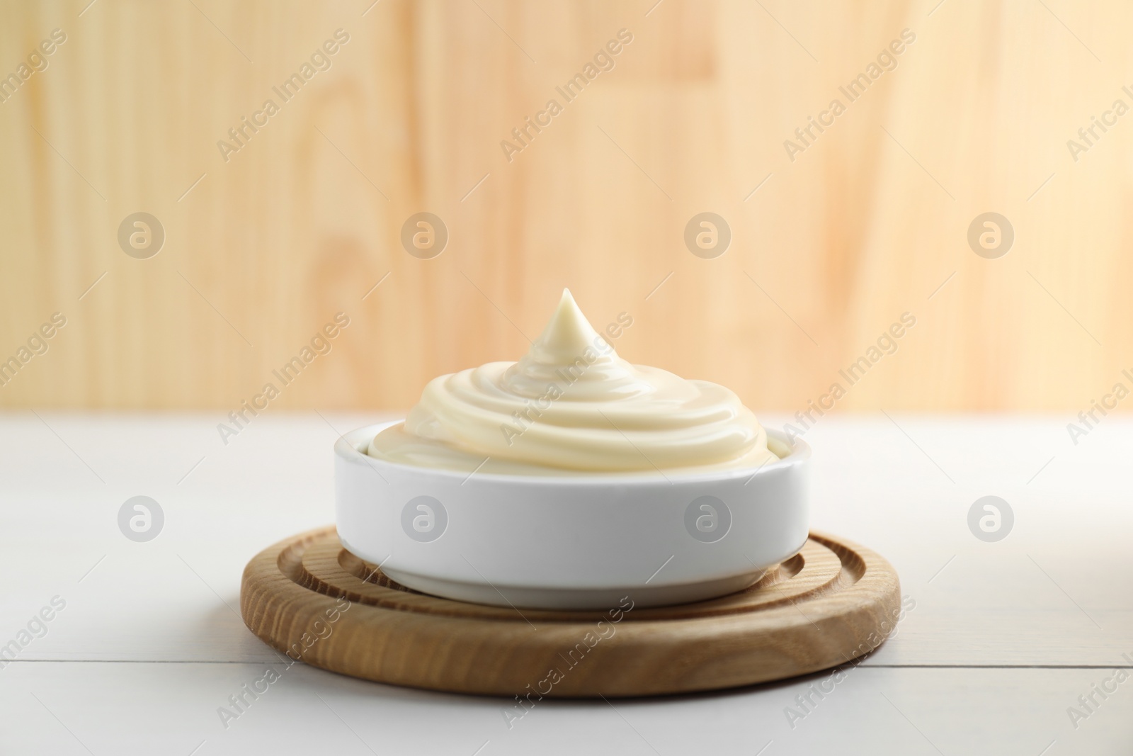 Photo of Fresh mayonnaise sauce in bowl on white wooden table