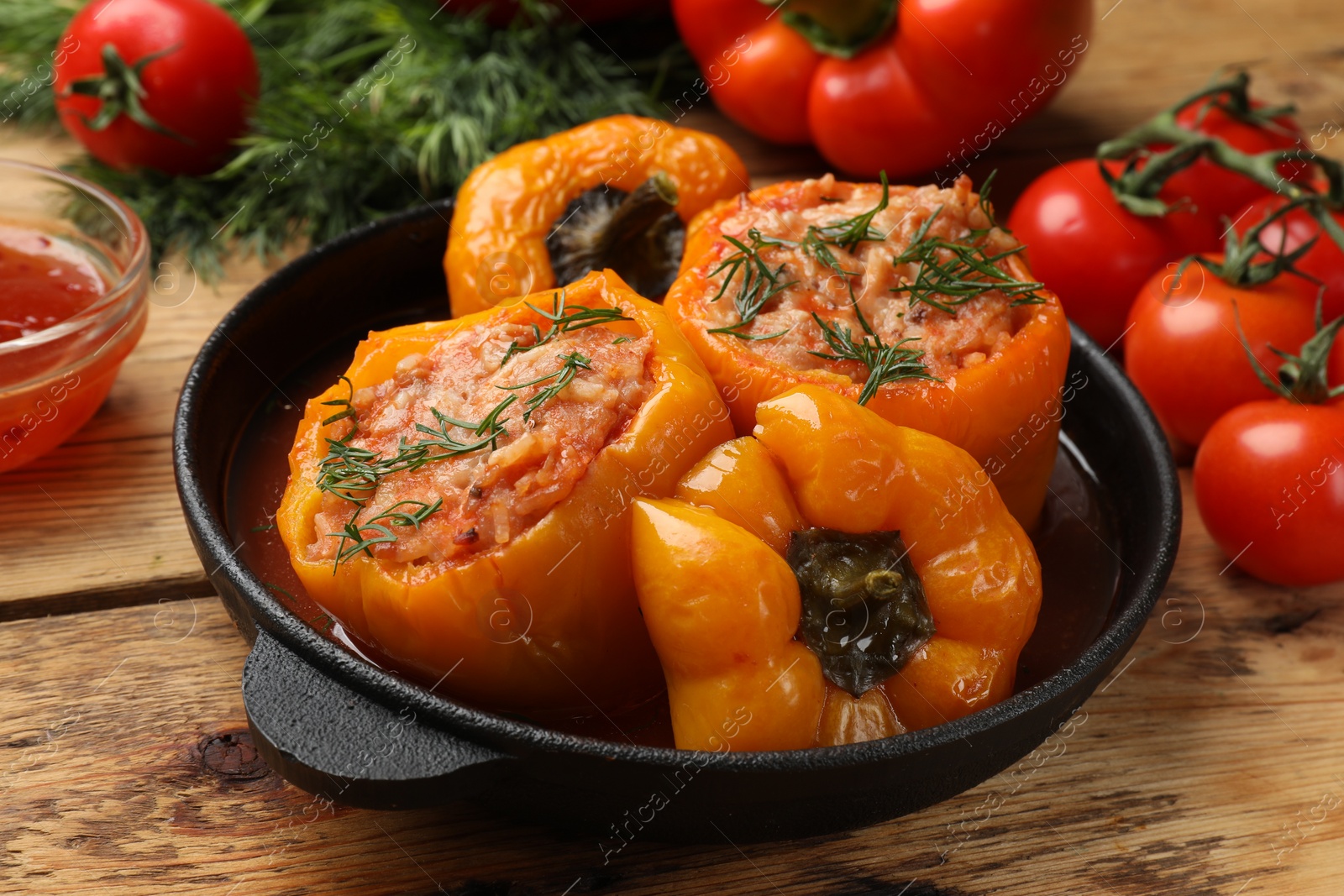 Photo of Tasty stuffed peppers in pan on wooden table, closeup