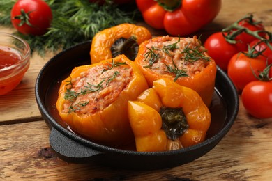 Photo of Tasty stuffed peppers in pan on wooden table, closeup