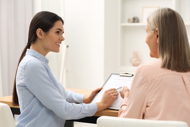 Notary consulting senior woman about Last Will and Testament in office, back view