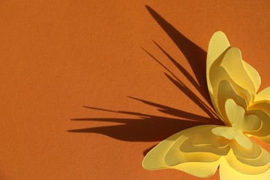 Photo of Yellow paper butterflies on orange background, above view. Space for text