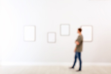 Young man in hall of modern art gallery, blurred view