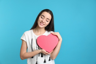 Photo of Portrait of beautiful young woman with decorative heart on color background