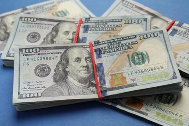 Photo of Many dollar banknotes on blue background, closeup. American national currency