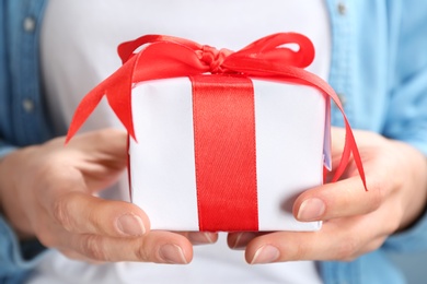 Photo of Young woman holding beautifully decorated gift box, closeup
