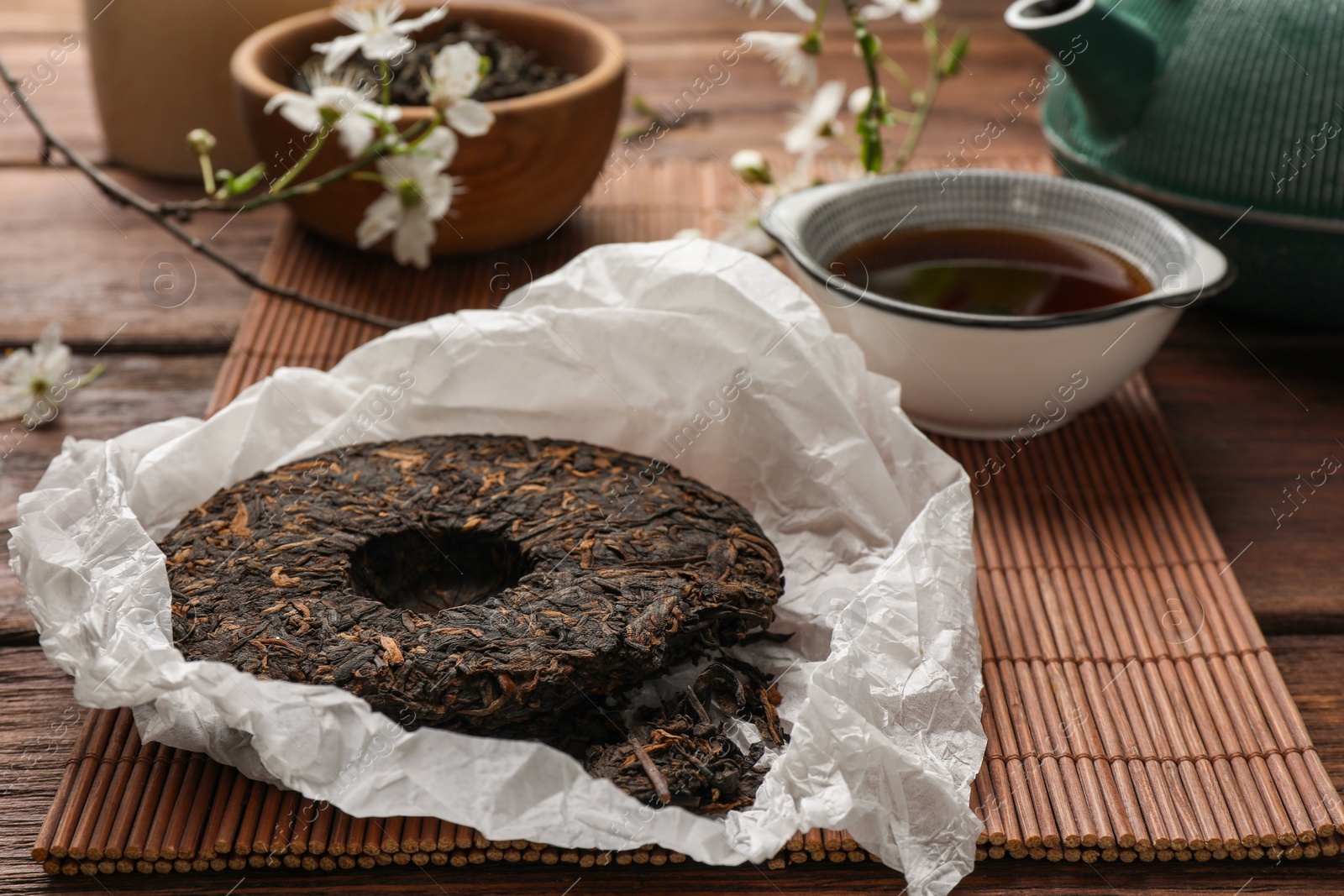 Photo of Broken disc shaped pu-erh tea on wooden table, closeup