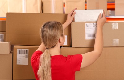 Post office worker taking parcel from rack indoors, back view