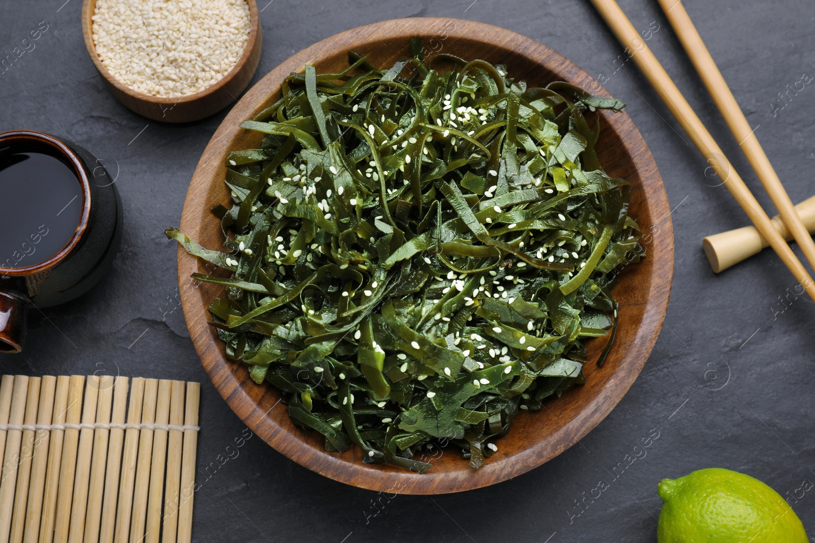 Photo of Fresh laminaria (kelp) seaweed served on black table, flat lay