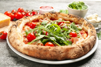 Photo of Tasty pizza with meat and arugula on grey table, closeup