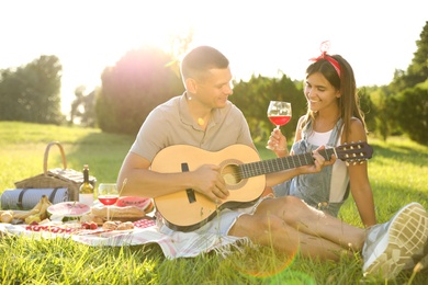 Photo of Happy couple with guitar on picnic in park