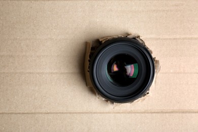 Photo of Hidden camera lens through torn in cardboard. Space for text
