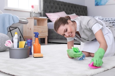 Woman cleaning carpet in bedroom