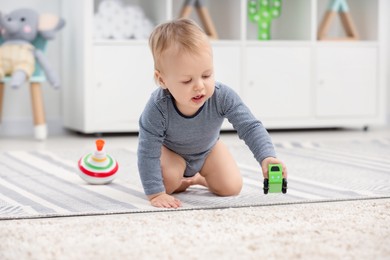 Photo of Children toys. Cute little boy playing with toy car on rug at home