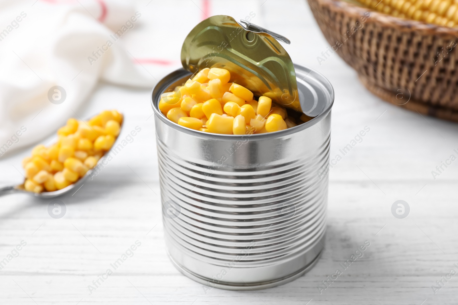 Photo of Can of preserved corn on white wooden table