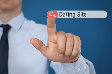 Man pointing at search bar with request Dating Site on blue background, closeup