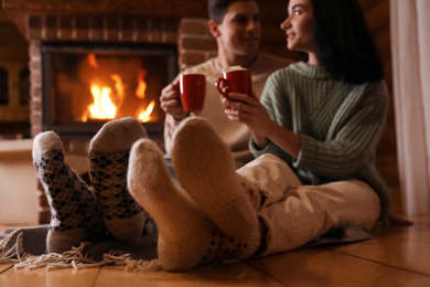 Lovely couple with sweet cocoa near fireplace indoors, focus on legs
