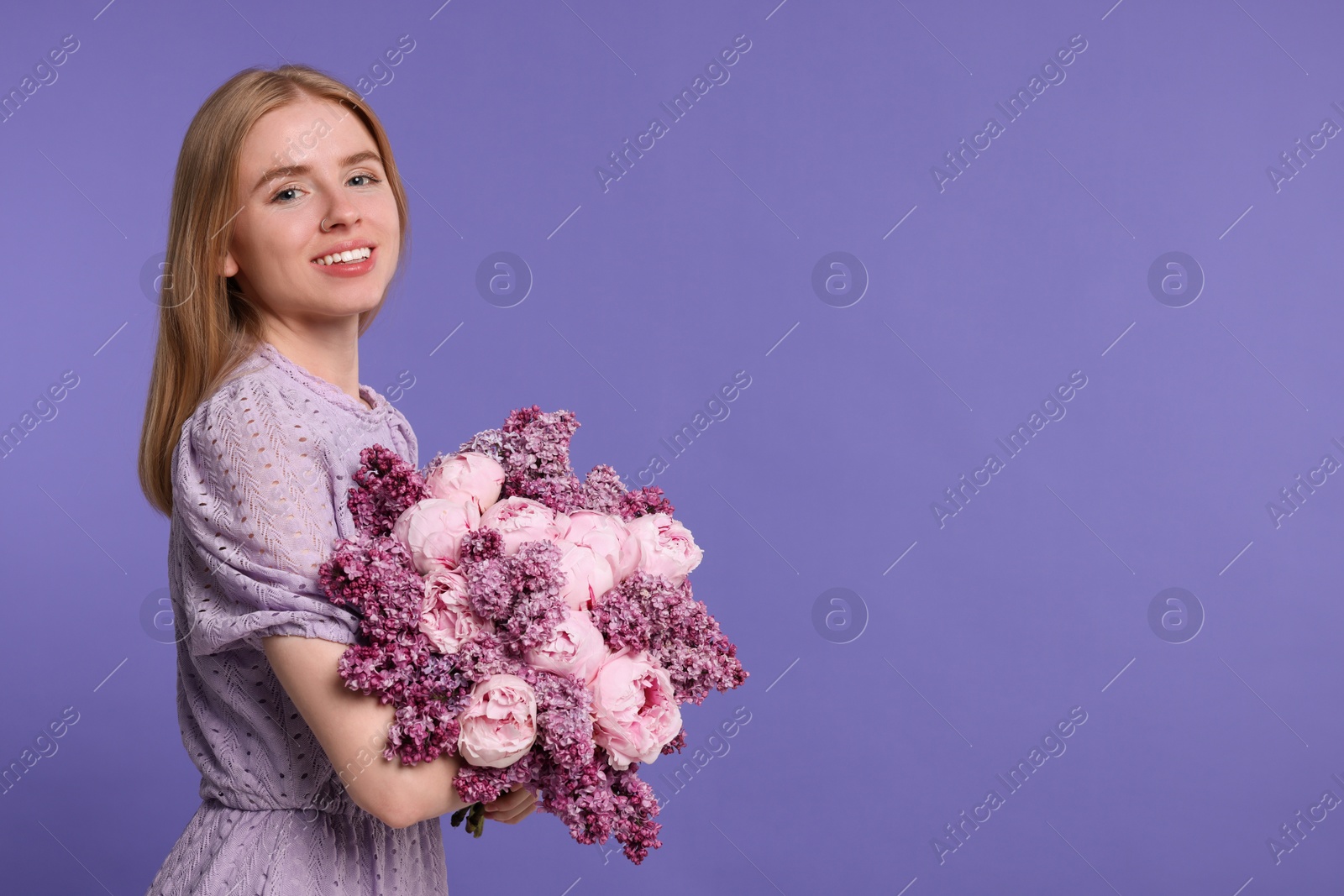 Photo of Beautiful woman with bouquet of spring flowers on purple background, space for text