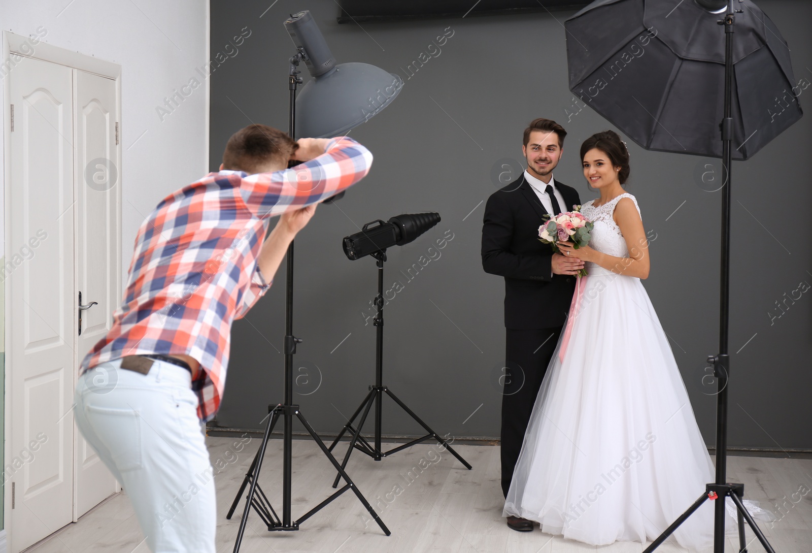 Photo of Professional photographer taking photo of wedding couple in studio