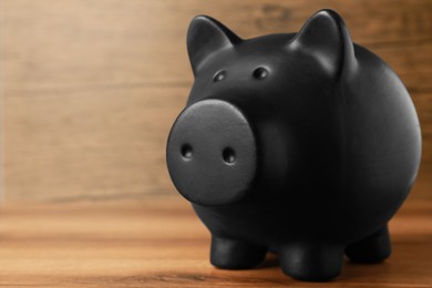 Photo of Ceramic piggy bank on wooden table, closeup. Space for text