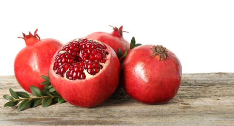 Photo of Fresh pomegranates and green leaves on wooden table against white background