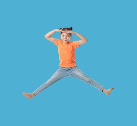 Image of Happy cute girl jumping on light blue background