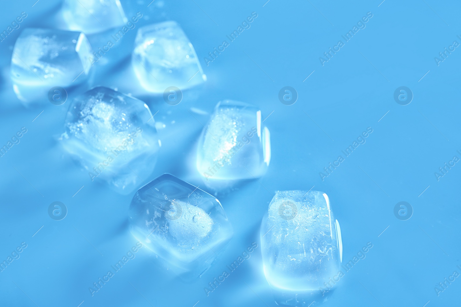 Photo of Transparent ice cubes on color mirror surface