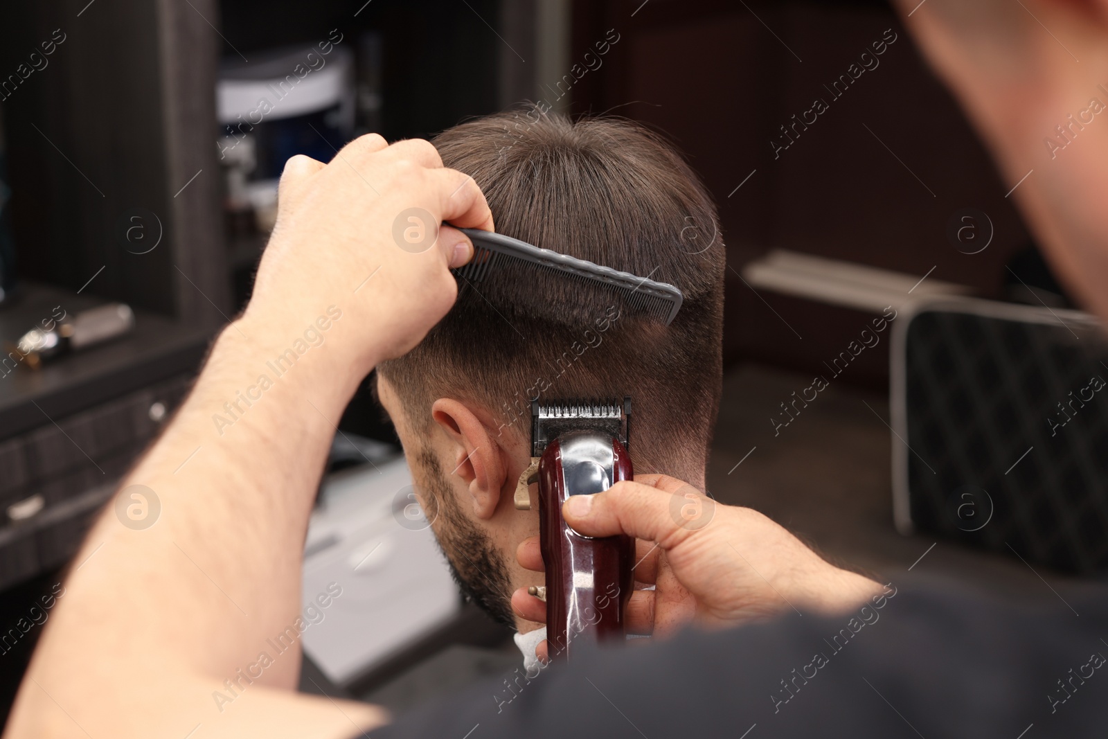 Photo of Professional hairdresser making stylish haircut in barbershop