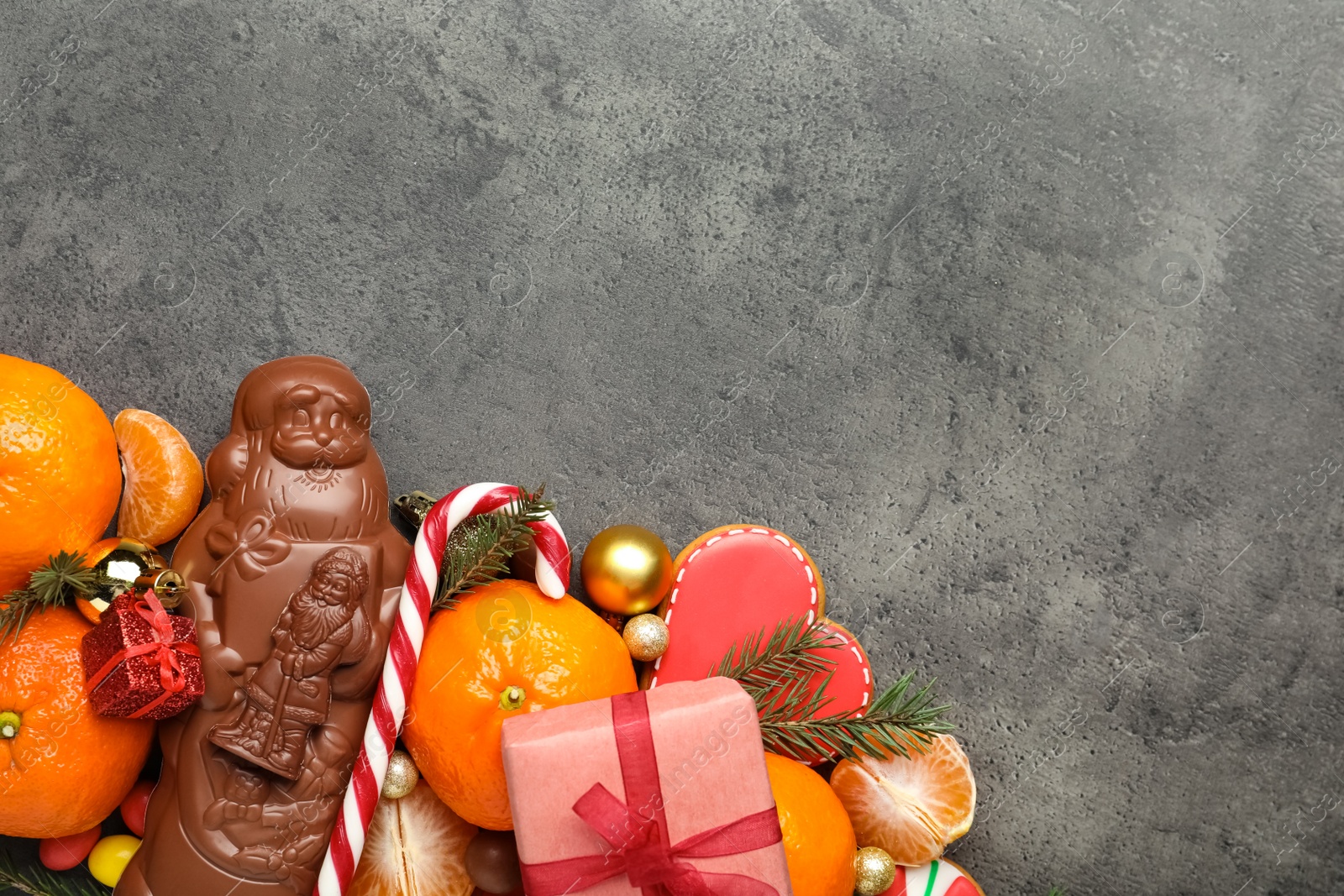 Photo of Flat lay composition with chocolate Santa Claus candies on grey table. Space for text