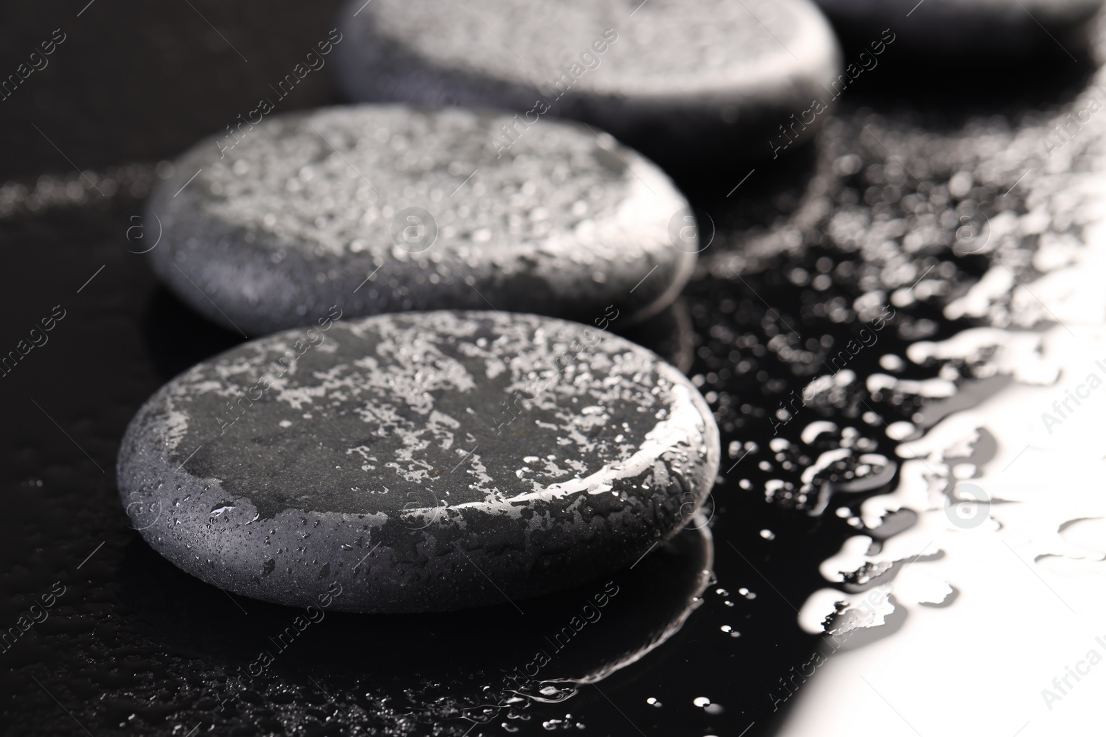 Photo of Grey spa stones with water drops on black background, closeup. Space for text