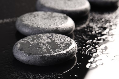 Photo of Grey spa stones with water drops on black background, closeup. Space for text