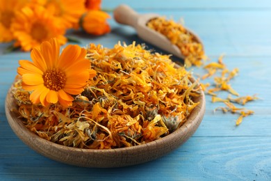 Plate of dry calendula flowers on light blue wooden table, closeup