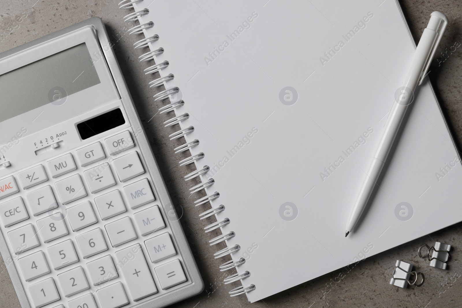 Photo of Ballpoint pen, notebook and calculator on gray table, flat lay