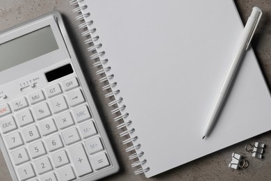 Photo of Ballpoint pen, notebook and calculator on gray table, flat lay