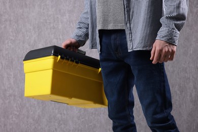 Young man with tool box on grey background, closeup