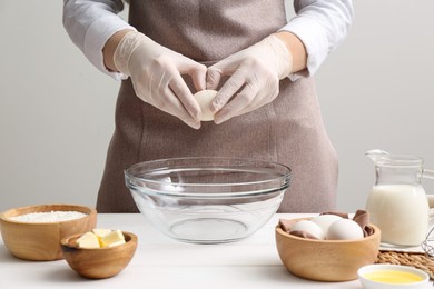 Photo of Woman preparing batter for crepes at white wooden table, closeup