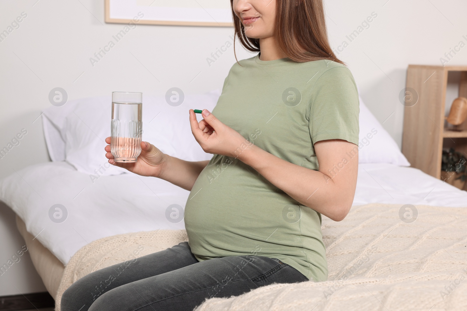 Photo of Pregnant woman taking pill at home, closeup