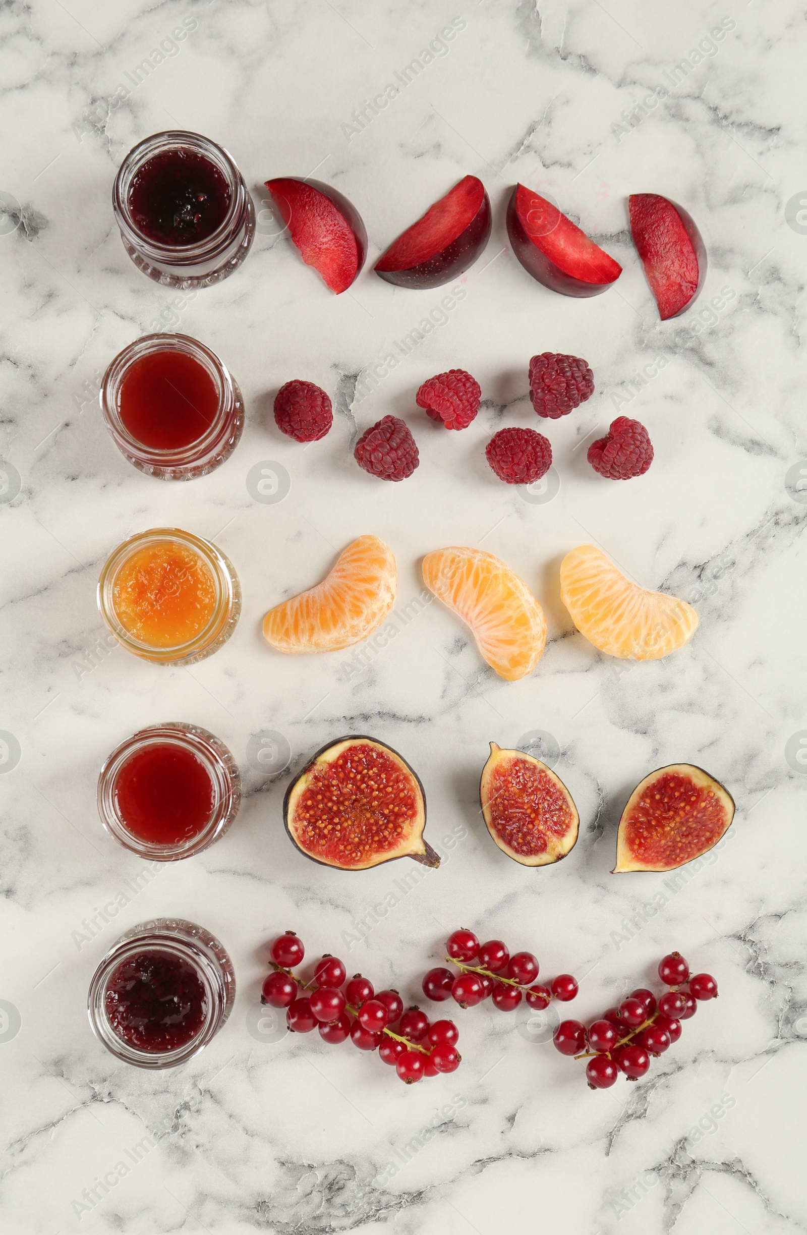 Photo of Jars of different jams and fresh ingredients on white marble table, flat lay