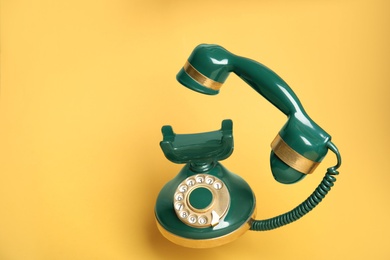 Photo of Green vintage corded phone on yellow background