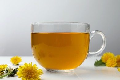 Delicious fresh tea and beautiful dandelion flowers on white table