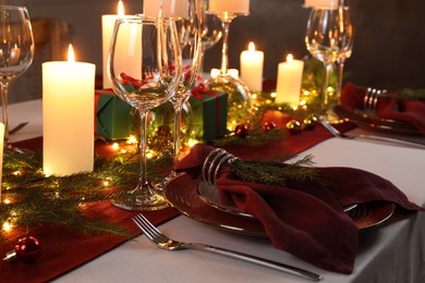 Photo of Christmas table setting with burning candles and festive decor