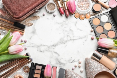 Many different makeup products, shoes and spring flowers on marble background, flat lay. Space for text