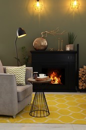 Photo of Beautiful fireplace, armchair, table and different decor in living room. Interior design