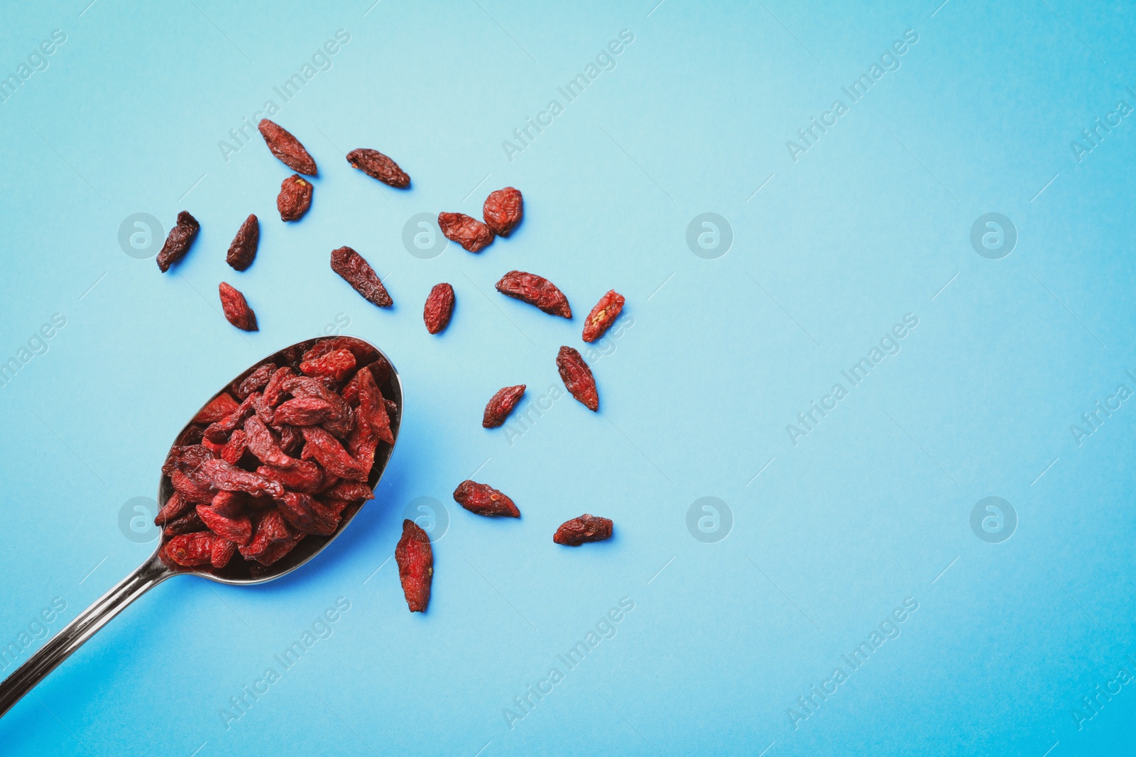 Photo of Dried goji berries on light blue background, flat lay. Space for text