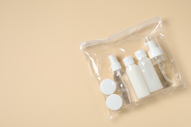 Cosmetic travel kit in plastic bag on beige background, top view and space for text. Bath accessories