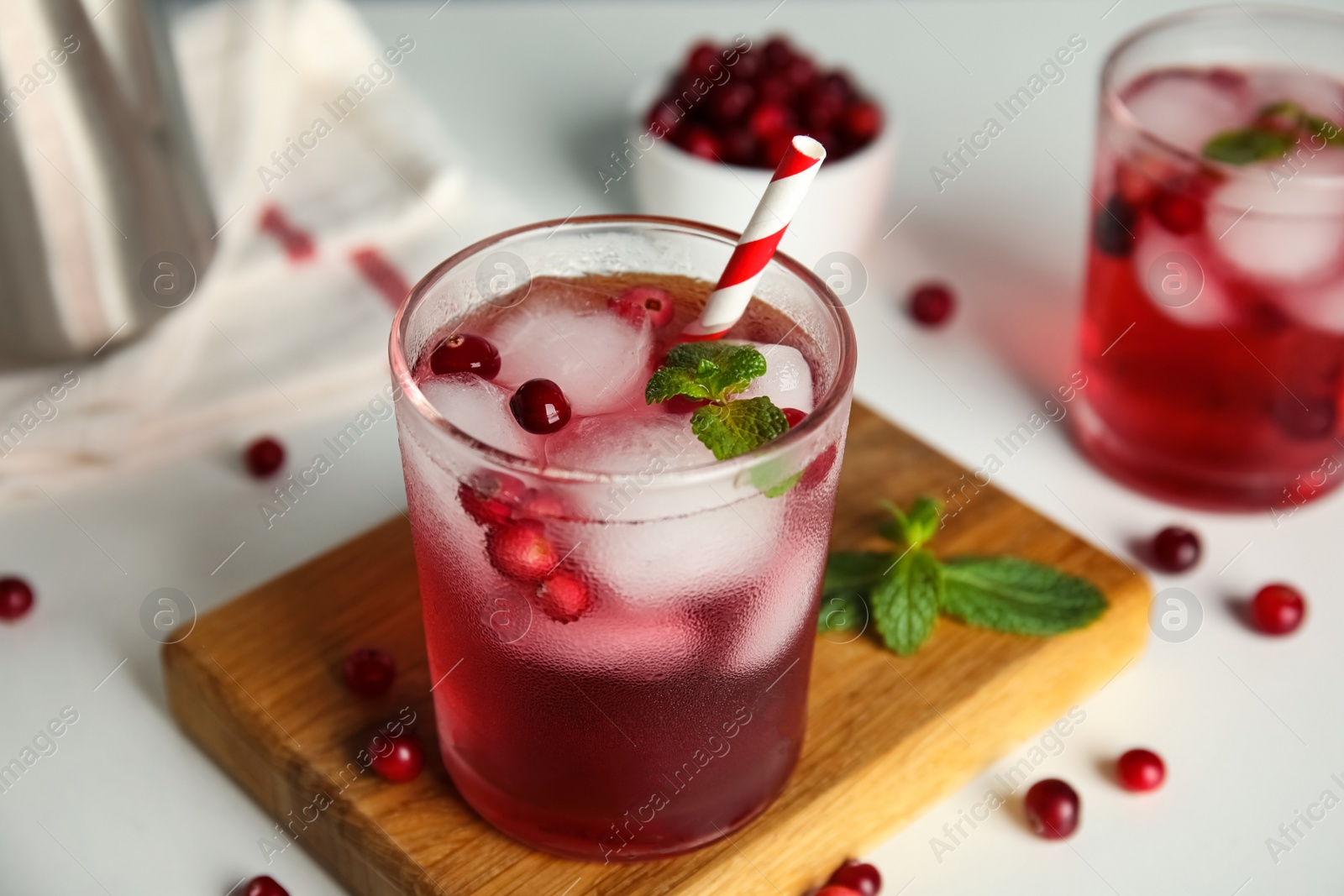 Photo of Tasty refreshing cranberry cocktail with mint on white table