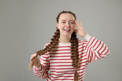 Woman with braided hair on grey background