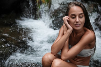 Photo of Beautiful young woman in light blue bikini near mountain stream outdoors. Space for text