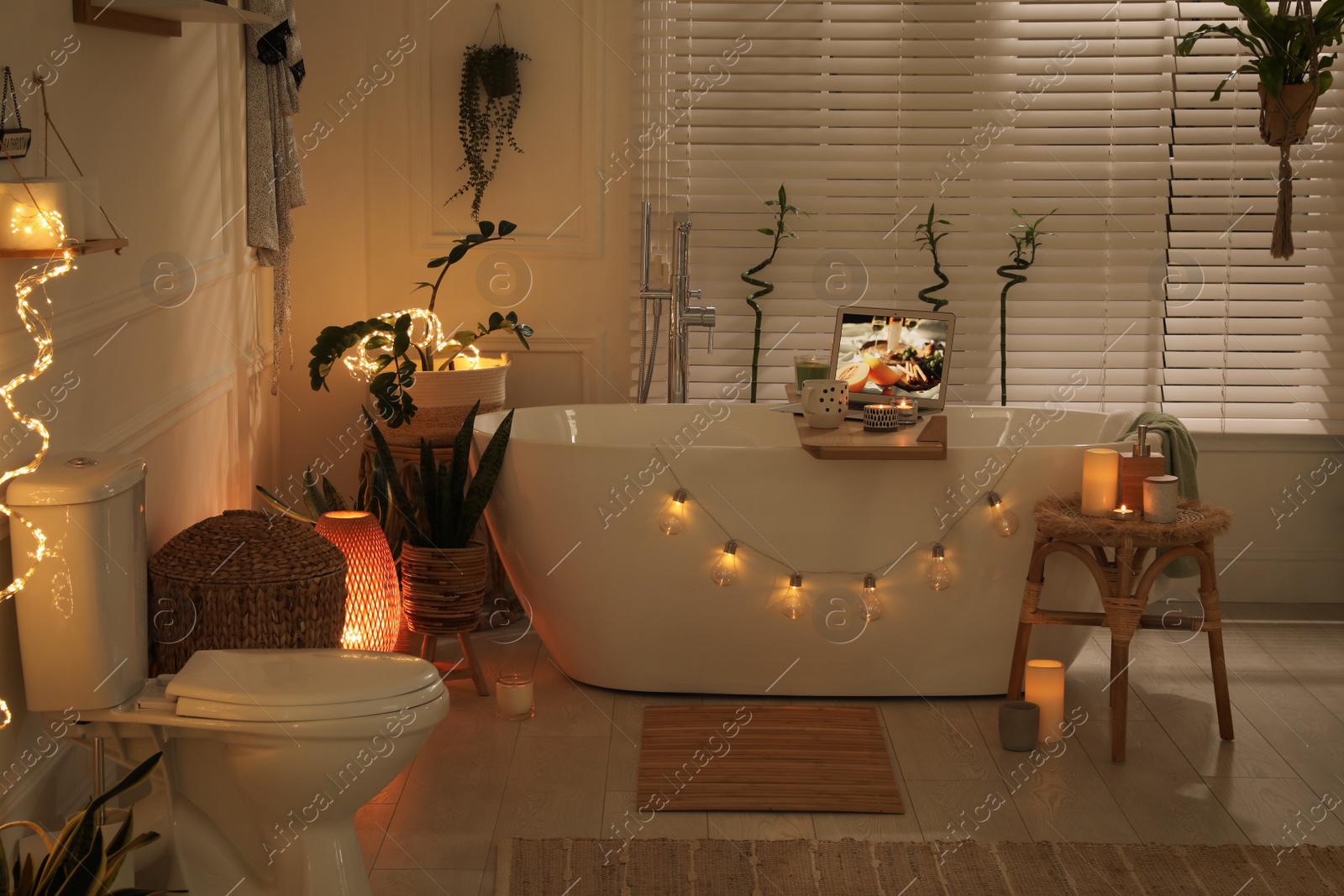 Photo of Stylish bathroom interior with green houseplants and string lights. Idea for design