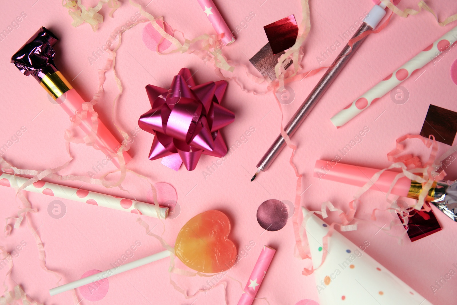 Photo of Party blowers, lollipop and festive decor on pink background, flat lay
